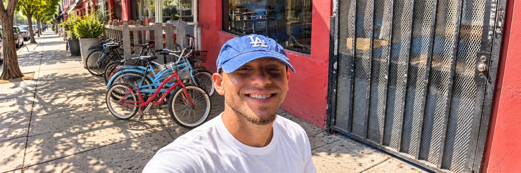 Joey smiling in a blue cap outside a bicycle shop